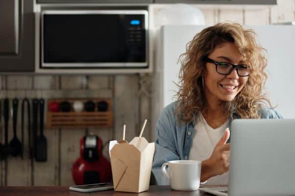 Woman in her kitchen smiles during an online language class