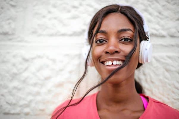 Smiling woman listens to a language audio course like Pimsleur 