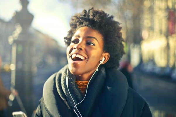 Woman with earphones talks in Swahili while walking down the street