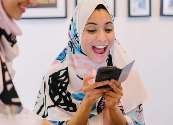 A woman is excited as she learns a language with a Duolingo alternative like Lingodeer or Babbel