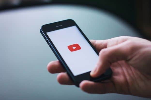 Man holding smartphone with YouTube symbol on screen