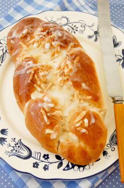 A loaf of pulla, a traditional Finnish bread served with coffee, sits on a round plate. There is a knife for slicing the bread.
